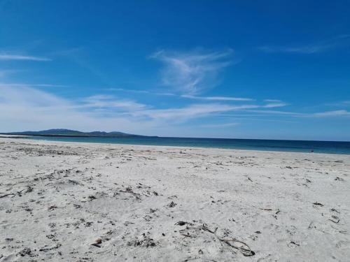 a sandy beach with a blue sky and the ocean at Loch an Eilean Pod Isle of South Uist in Pollachar