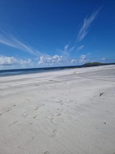 an empty beach with footprints in the sand at Loch an Eilean Pod Isle of South Uist in Pollachar
