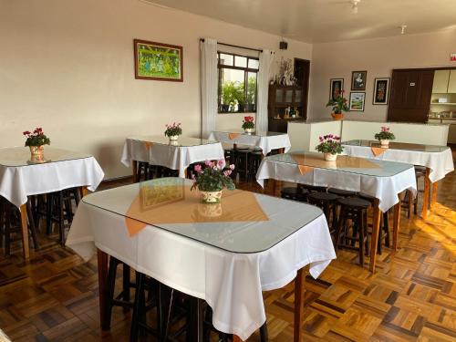 ein Restaurant mit Tischen und Stühlen mit Blumen darauf in der Unterkunft Pousada Irmãs Franciscanas in Lages