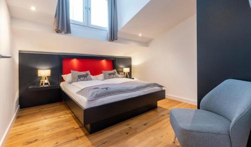 a bedroom with a bed with a red headboard and a chair at Hotel Residenz Hochalm - Joker Card Partner in Saalbach Hinterglemm