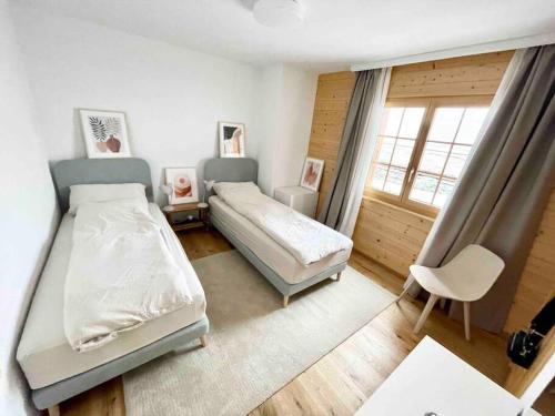 a bedroom with two beds and a chair and a window at Apartment with stunning view! Ski-in, ski-out in Villars-sur-Ollon