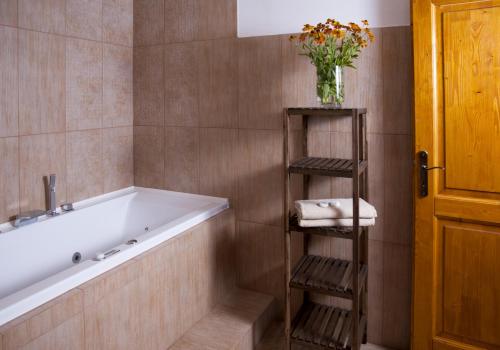a bathroom with a tub and a vase with flowers at Penzion Jízdárna Hejtmánkovice in Broumov