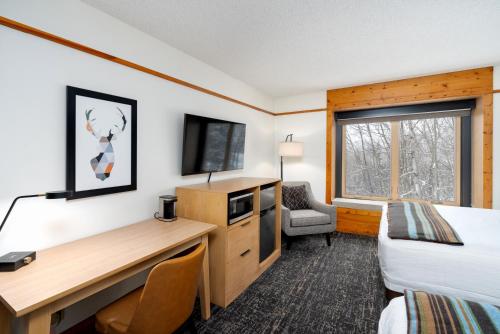 a hotel room with a bed and a desk with a computer at Caribou Highlands Lodge in Lutsen