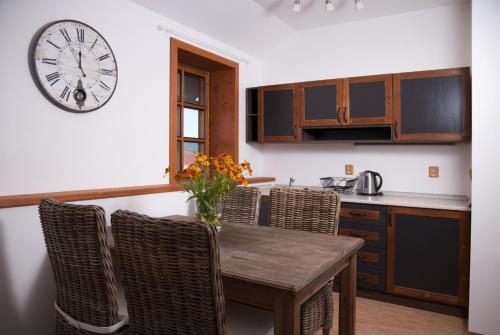 a kitchen with a table and chairs and a clock on the wall at Penzion Jízdárna Hejtmánkovice in Broumov