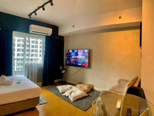 Cette chambre comprend un lit, une table et une télévision. dans l'établissement Modern Brand New Condo in Grace Residence Taguig, à Manille