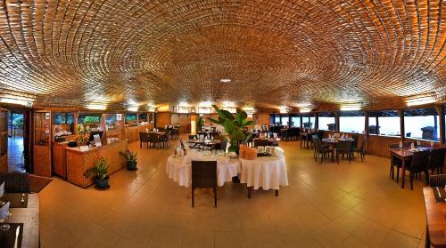 un restaurant avec des tables et des chaises et un grand plafond dans l'établissement Royal Tahitien, à Papeete