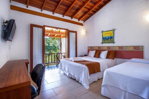 a bedroom with two beds and a balcony at Hotel Praia do Portinho in Ilhabela
