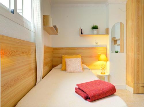 um pequeno quarto com uma cama com um cobertor vermelho em Fuengirola playa carina em Fuengirola
