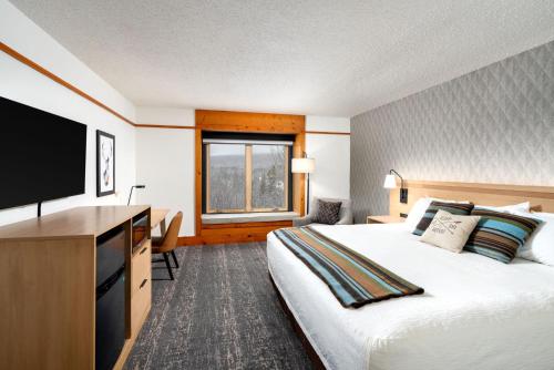 a hotel room with a large bed and a flat screen tv at Caribou Highlands Lodge in Lutsen