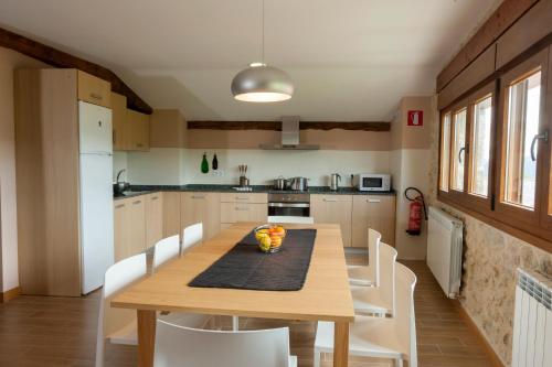 eine Küche mit einem Holztisch und weißen Stühlen in der Unterkunft Casa Rural Aranaratxe in Aranarache