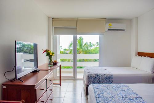a bedroom with two beds and a tv and a window at Blu Hotel by Tamaca in Santa Marta