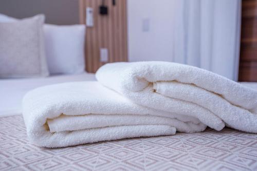 a pile of white towels sitting on a bed at Hotel Praia do Portinho in Ilhabela