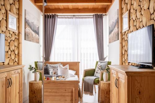 a living room with a tv and a couch and a window at Willa Mały Dworek in Zakopane