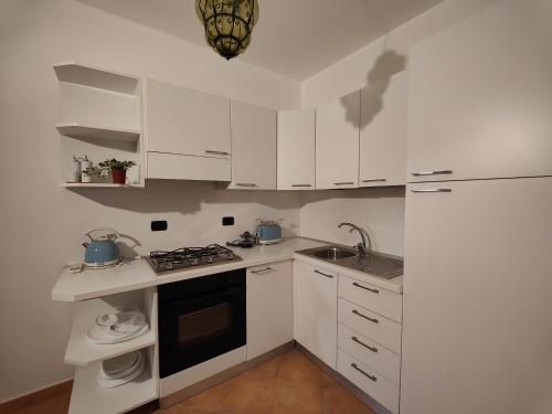 eine Küche mit weißen Schränken, einer Spüle und einem Herd in der Unterkunft Pan Di Zucchero in Nebida