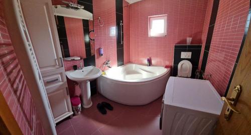 La salle de bains rose est pourvue d'une grande baignoire et d'un lavabo. dans l'établissement Apartman Azul, à Podastrana