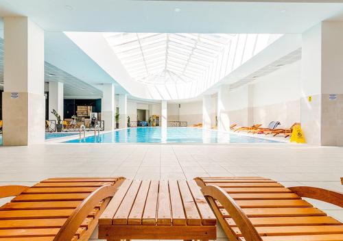 a swimming pool with two benches in a building at Oak Sky Apartment Spa & Fitness in Skopje