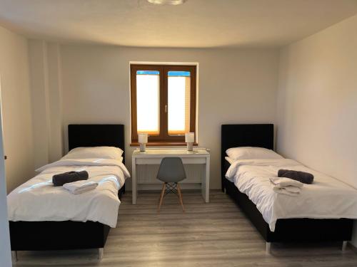 two beds in a room with a desk and a window at Apartment Golden Prague 78 in Vestec