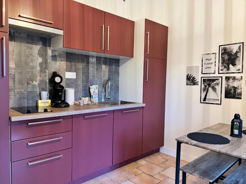 une cuisine avec des placards violets et une table dans l'établissement Hébergements indépendants proches aéroport de Nantes Atlantique et centre ville de Nantes, à Saint-Aignan-Grand-Lieu