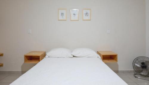 a bedroom with a white bed with two wooden tables at Casa Matia in Guadalajara