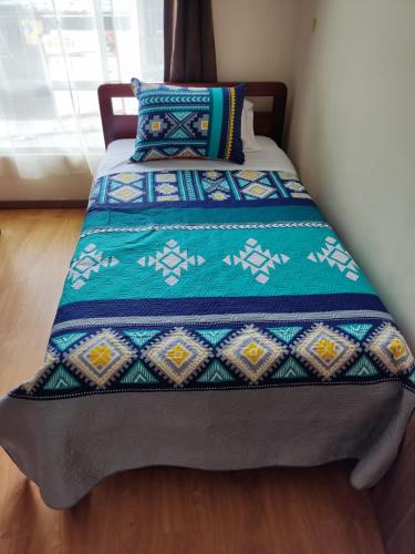 a bed with a quilt on top of it at Dulce Hogar in Loja