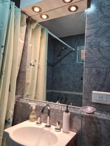 y baño con lavabo, ducha y espejo. en departamento maipu en Salta