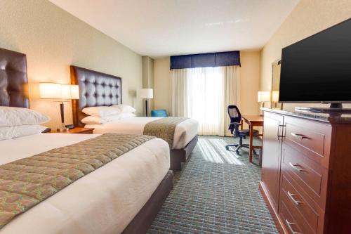 a hotel room with two beds and a flat screen tv at Drury Inn & Suites Gainesville in Gainesville