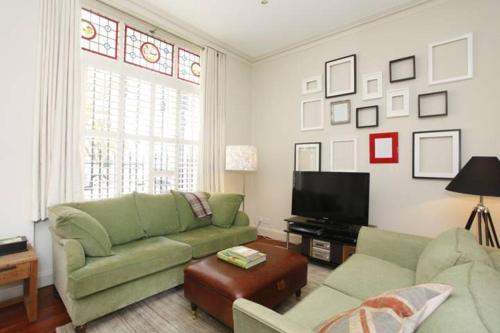uma sala de estar com um sofá verde e uma televisão em Your Place in Little Venice em Londres
