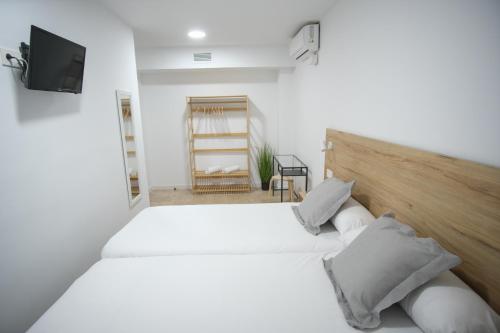 アリカンテにあるUrban Rooms Alicanteのテレビ付きの客室で、白いベッド2台が備わります。