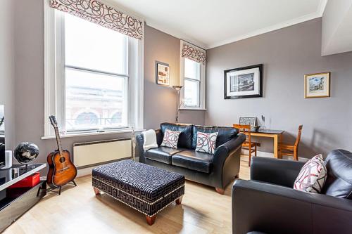 a living room with leather furniture and a guitar at Chic Farringdon Flat in London