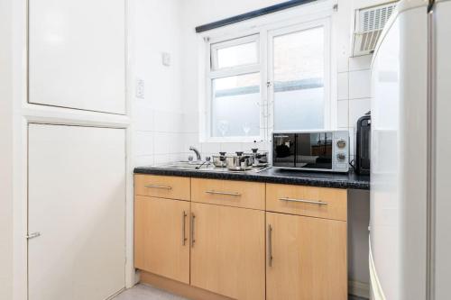 a kitchen with a sink and a microwave at Studio Flat 3, 20 mins to Central London in The Hyde