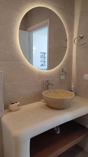 a bathroom with a sink with a round mirror at Aelia Mare Apartments Nr2 in Istérnia