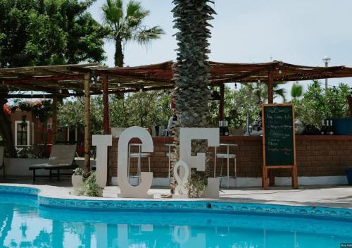 un cartel junto a una piscina frente a un complejo en La Estancia Chincha Hotel, en Chincha Alta