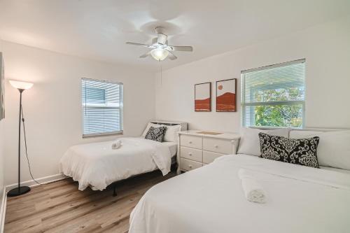 Habitación blanca con 2 camas y ventilador de techo. en Hidden Oasis ** Stunning 2 BR ** Sunset Shores, en West Palm Beach