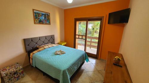 a bedroom with a bed and a television and a window at Piscina Climatizada em condomínio - Atibaia SP in Atibaia