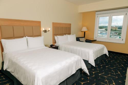 サン・サルバドルにあるHoliday Inn San Salvador, an IHG Hotelのベッド2台と窓が備わるホテルルームです。