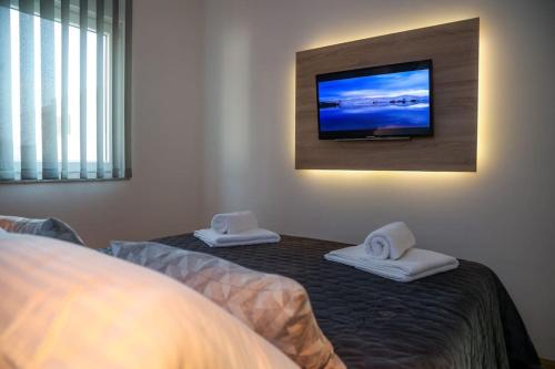 a bedroom with a bed and a flat screen tv on the wall at Apartment Mare Blu in Kožino