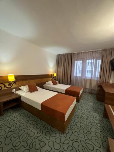 um quarto de hotel com duas camas e uma televisão em Garsoniere Aby em Turnu Măgurele