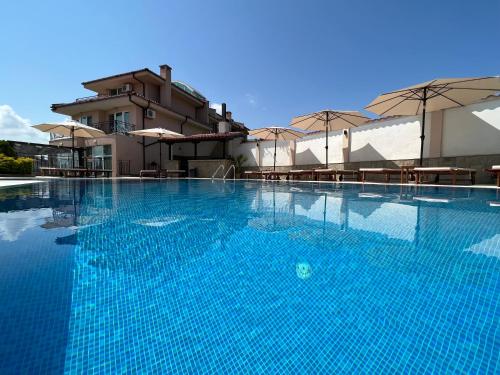 a large blue swimming pool with tables and umbrellas at Villa Mia in Sozopol