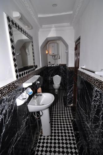 a black and white bathroom with a sink and a toilet at Riad Khouloud in Fès