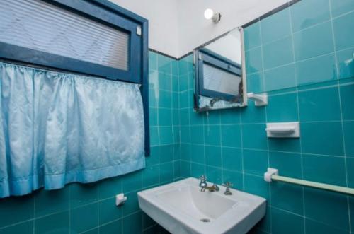 Baño de azulejos verdes con lavabo y espejo en Georgy house, en Punta del Este