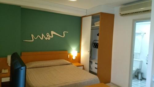 a bedroom with a bed and a green wall at Bristol Praia do Canto Apart Hotel in Vitória
