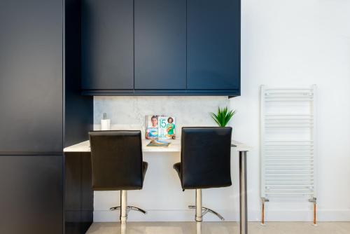 a kitchen with blue cabinets and two chairs at Luxe Maisonette- Parking, 4K TVs, LEDs, Local Snacks and more! in Bath