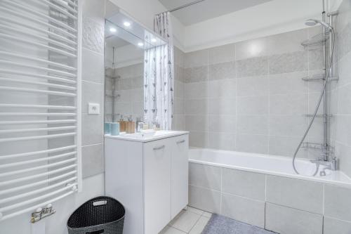 La salle de bains blanche est pourvue d'un lavabo et d'une baignoire. dans l'établissement Cozy - Free Parking - 15mn from Paris Montparnasse, à Clamart