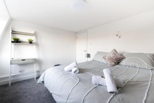 a white bedroom with a large bed with white walls at Luxe Maisonette- Parking, 4K TVs, LEDs, Local Snacks and more! in Bath