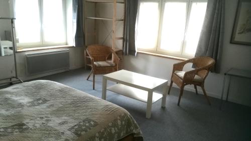 a bedroom with a bed and two chairs and a table at Le Lohrnest in Lohr