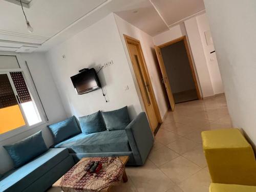 a living room with a blue couch and a tv at Chahrazad Hotspot -Balcony-Washing Machine -Kitchen in Saidia 