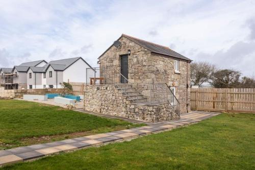 a stone house in a yard with a fence at Cornwall - Unique two storey barn in St Austell