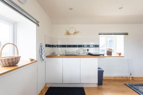 a kitchen with white cabinets and a counter top at Cornwall - Unique two storey barn in St Austell