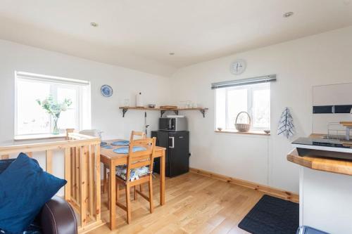 a living room with a table and a kitchen at Cornwall - Unique two storey barn in St Austell