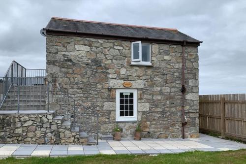 a stone building with a window and a fence at Cornwall - Unique two storey barn in St Austell
